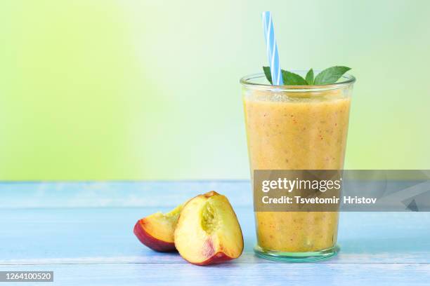 homemade smoothie with fresh peach on a blue wood background - peach smoothie stock pictures, royalty-free photos & images