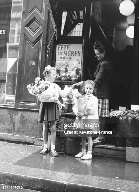 Deux petites filles achètent des fleurs pour la fête des mères, le 8 juin 1947, à Paris, France.