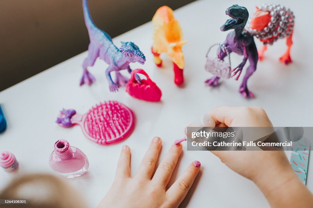 Child painting Finger Nails Pink, and giving Dinosaur Figurines a feminine Makeover