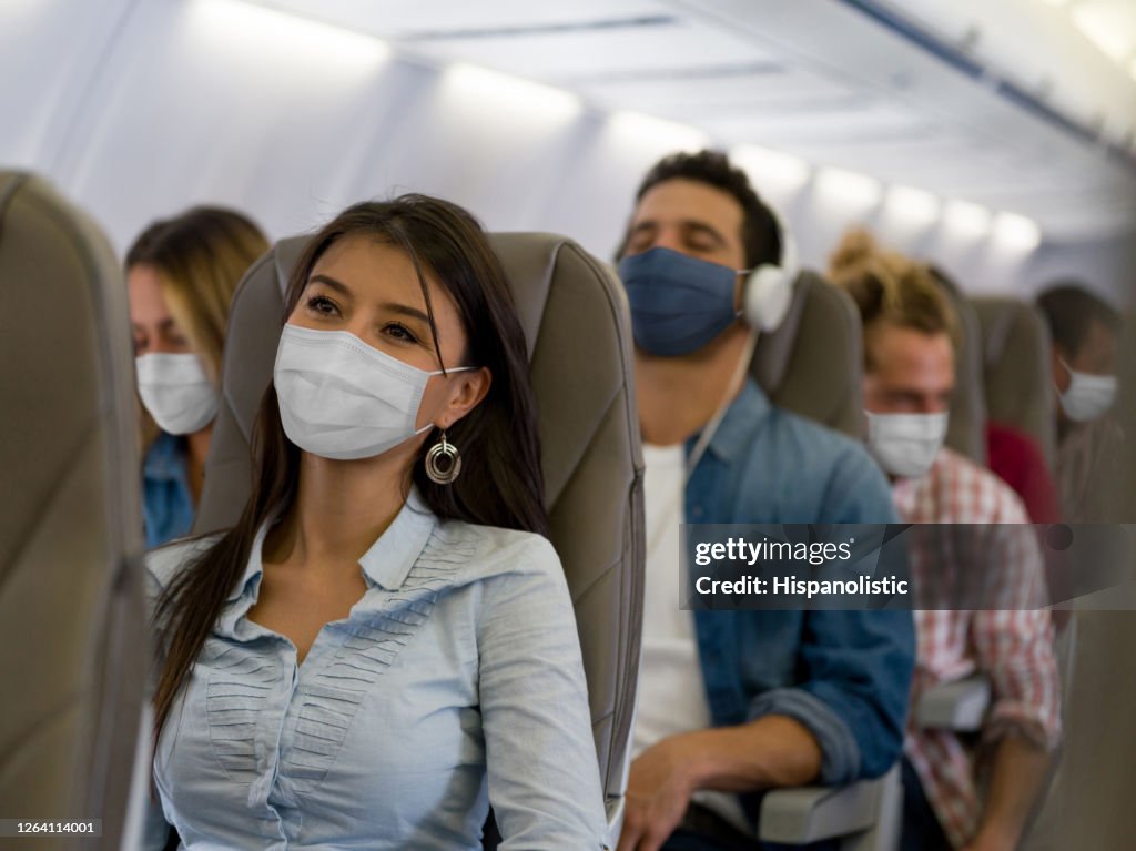 Frau, die mit dem Flugzeug mit einer Gesichtsmaske unterwegs ist
