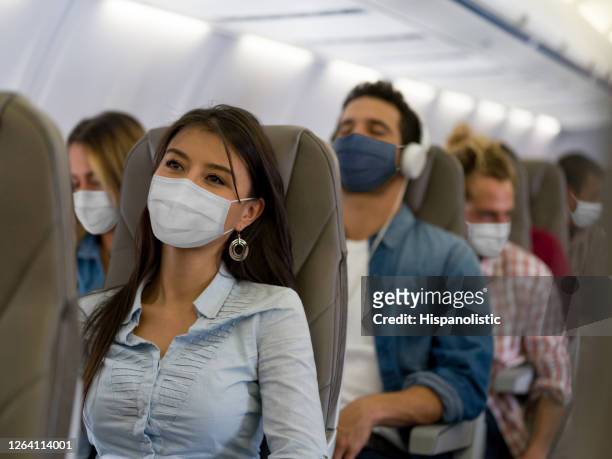 vrouw die door vliegtuig reist dat een facemask draagt - coronavirus airport stockfoto's en -beelden