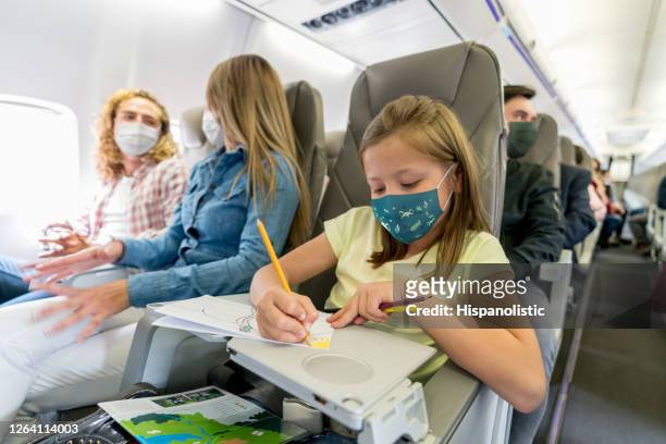 happy girl traveling and coloring in the plane wearing a facemask - covid-19 air travel stock pictures, royalty-free photos & images