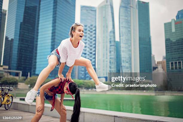 glückliche freundinnen spielen springfrosch und spaß haben - bockspringen stock-fotos und bilder