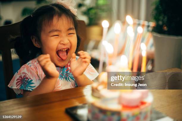 little girl looking at the candle on a birthday cake at home - birthday cake ストックフォトと画像