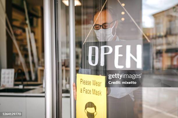 man with a sign requesting to wear face mask on reopening of shop - serbia covid stock pictures, royalty-free photos & images
