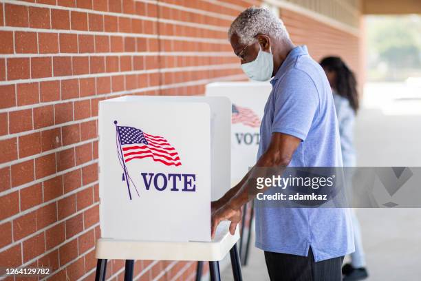 uomo nero anziano che vota con una maschera - elezione foto e immagini stock