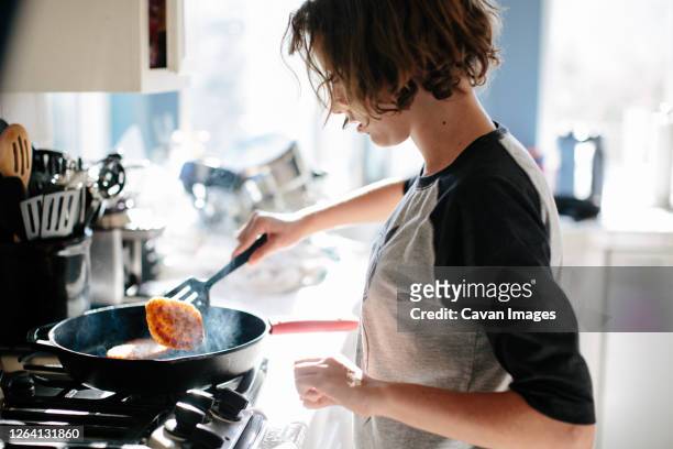 teen girl flips a steaming hash brown in a cast iron pan - fried stock pictures, royalty-free photos & images