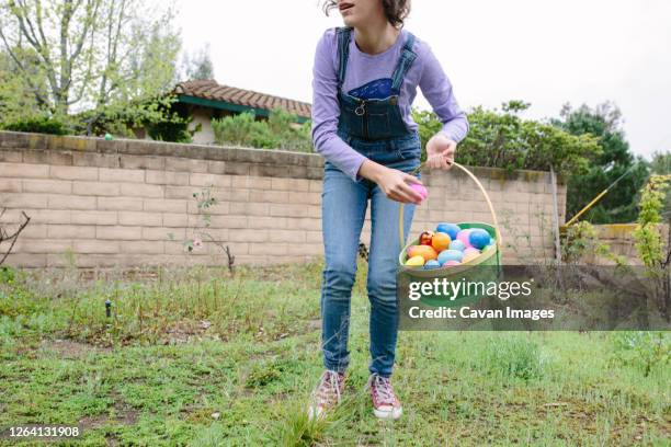 teen girl collects plastic eggs on easter to put in her basket - easter basket stock pictures, royalty-free photos & images