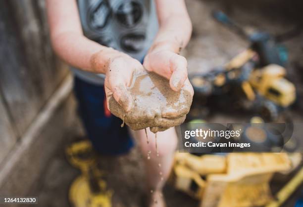 close up of a child's cupped hands holding mud in a sandbox. - zandbak stockfoto's en -beelden