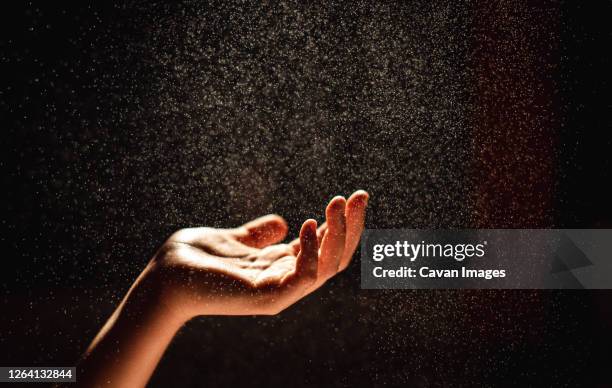 hand reaching into a sparkling mist against a black background. - dust dark fotografías e imágenes de stock