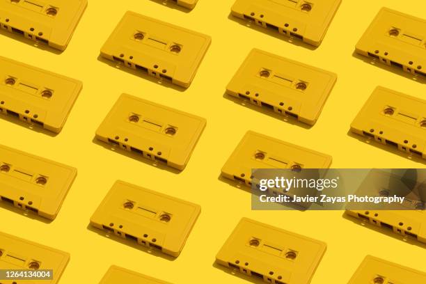 many yellow cassette tapes on yellow background - nostalgia background stock pictures, royalty-free photos & images