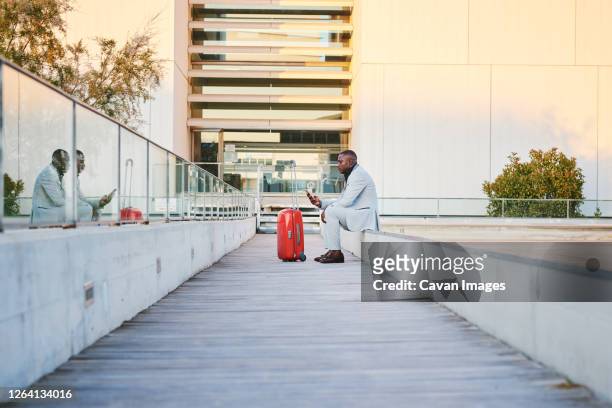 traveler with a red suitcase and a cell phone - guy with phone full image ストックフォトと画像