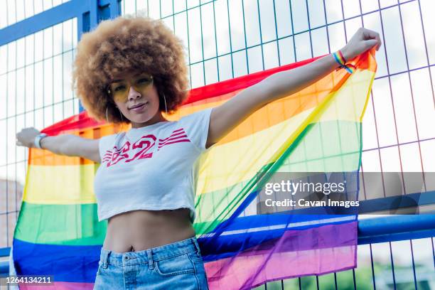 woman holding her gay pride flag on a bridge - gay flag stockfoto's en -beelden