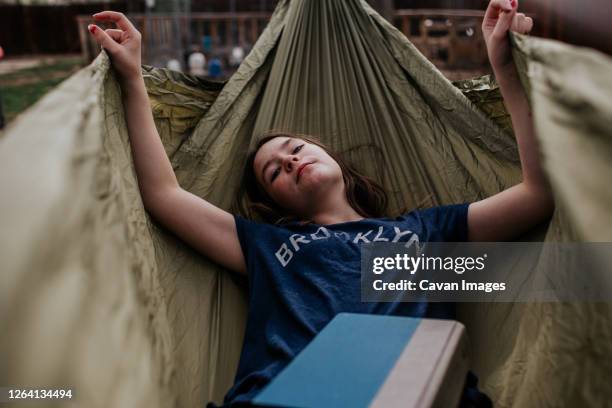 teen girl laying in hammock with a book - girl nap book stock pictures, royalty-free photos & images