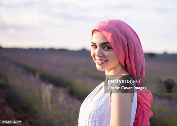 woman with pink cancer scarf in a lavender field - krebsschleife stock-fotos und bilder