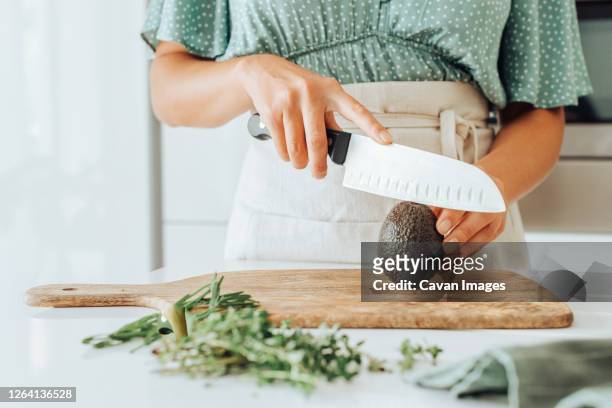 close up of female hands holding a kitchen knife to cut avocado - knife kitchen stock pictures, royalty-free photos & images
