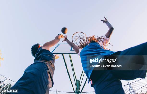 latin and african women play basketball - basketball teenager stock-fotos und bilder