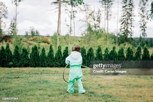 young girl playing with a hose in the yard in the rain at home - family sports centre laughing stock pictures, royalty-free photos & images