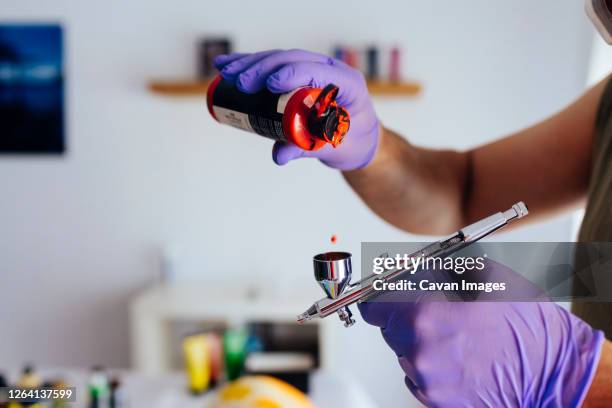 close up of painter's hands recharging his airbrush. - airbrush stock-fotos und bilder