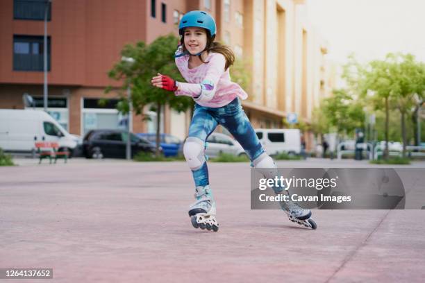 girl on the street skates with inline skates and helmet - patina fotografías e imágenes de stock