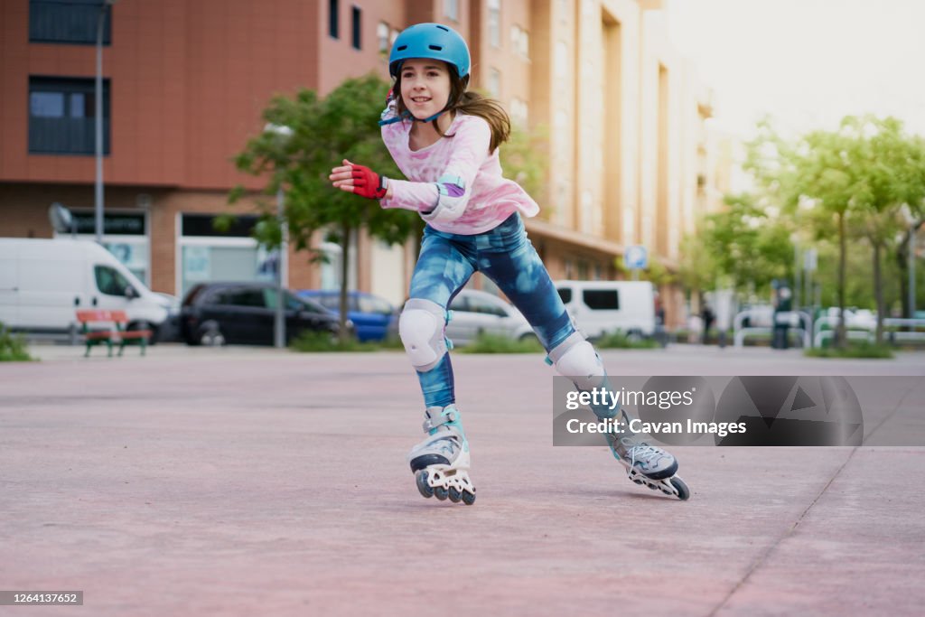 Girl on the street skates with inline skates and helmet