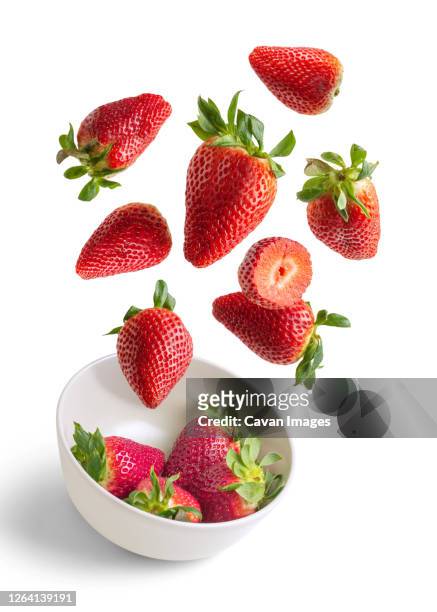 strawberries flying in white bowl isolated from the background - strawberry stock pictures, royalty-free photos & images