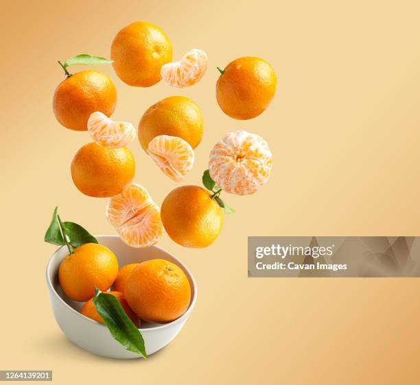 tangerines flying isolated from orange background with copy spac - mandarine stock-fotos und bilder