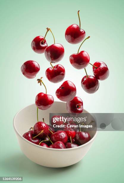 cherries flying on green background - cherry stock pictures, royalty-free photos & images