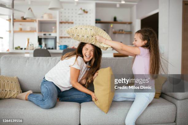 madre soltera y su niña están luchando almohadas foto de stock - lucho en familia fotografías e imágenes de stock