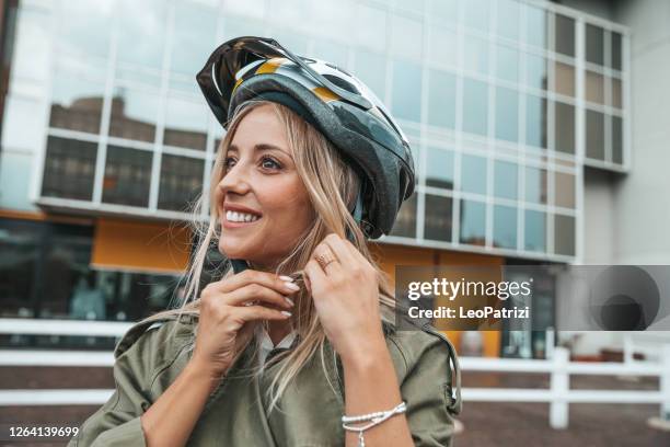 femme mettant le casque sur et prêt à monter - biking city photos et images de collection