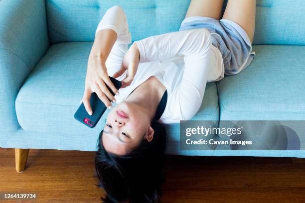 asian teenage girl lay down using mobile phone - child lying down stock pictures, royalty-free photos & images