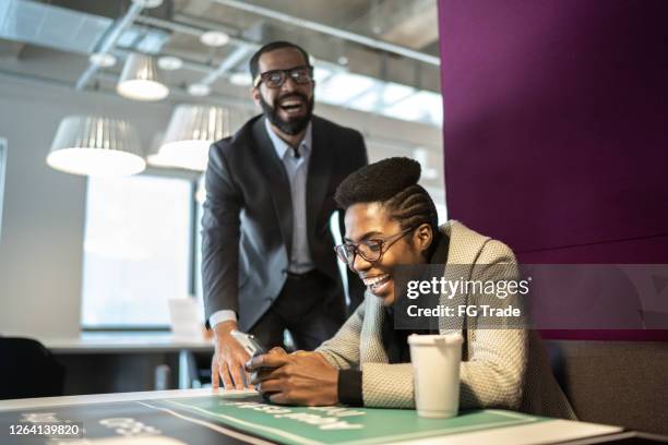 glückliche kollegen lachen gemeinsam mit dem handy im büro - 2 men chatting casual office stock-fotos und bilder