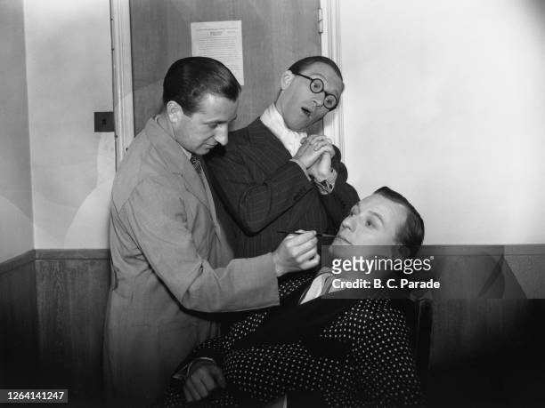 British comedian Arthur Askey watches as British actor Richard Murdoch sits in the make-up chair during production on the film version of their BBC...