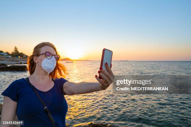 tourist woman with face mask on sunset beach selfie in mediterranean - denia stock pictures, royalty-free photos & images
