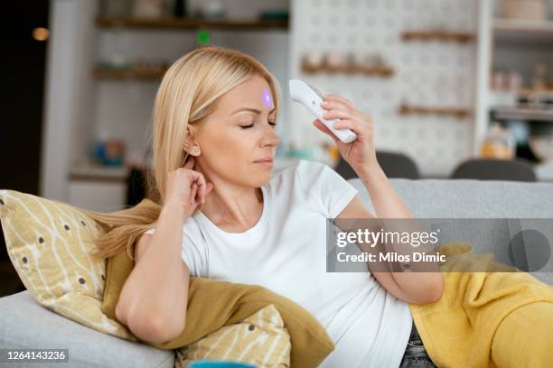 femme malade avec le thermomètre s’asseyant sur la photo de stock de lit - thermomètre à affichage digital photos et images de collection