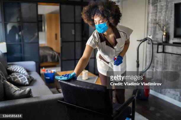 empregada doméstica que trabalha em um hotel fazendo serviço de quarto usando uma máscara facial e desinfetando devido à pandemia covid-19 - cleaning lady - fotografias e filmes do acervo