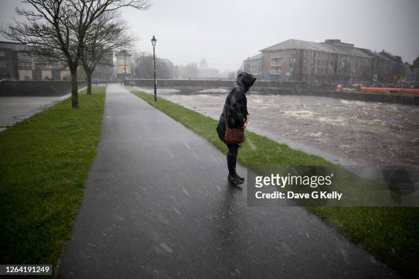 woman caught in storm - rivier gras oever stockfoto's en -beelden