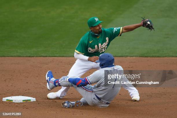 Elvis Andrus of the Texas Rangers slides in safely at second base on a double ahead of the tag by Marcus Semien of the Oakland Athletics in the top...