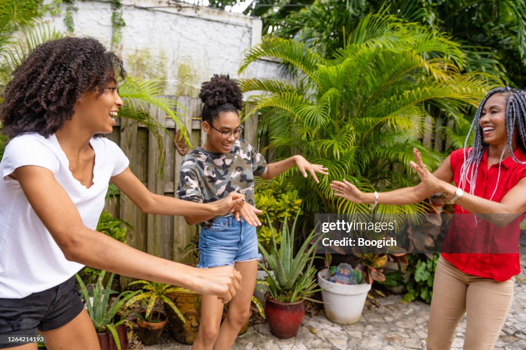 Two Teenage African American Sisters Dancing with their Mother in the Backyard in Miami