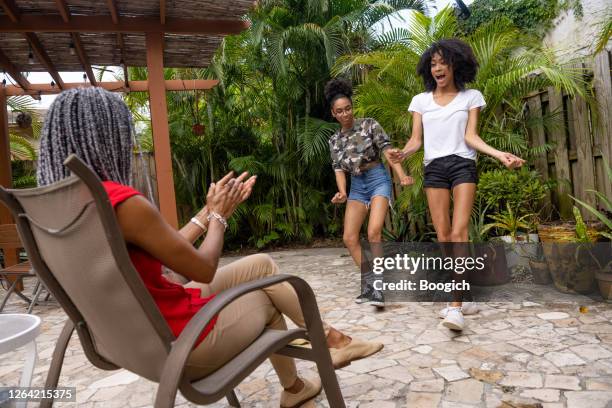 two teenage african american sisters dancing for their mom in the backyard at home in miami - sister act stock pictures, royalty-free photos & images