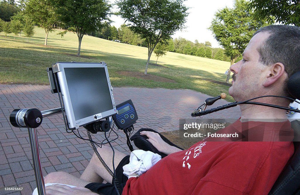 Man with a disability utilizing a mouthpiece to give commands to communications system that allows him to communicate.