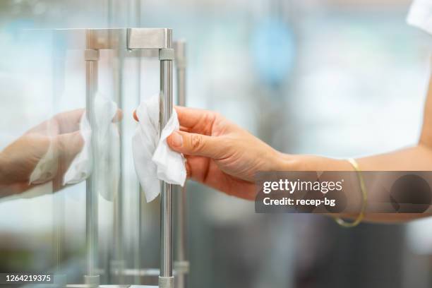 close-up photo of woman`s hand while disinfecting handle of refrigerator in supermarket before opening door - wet wipe stock pictures, royalty-free photos & images