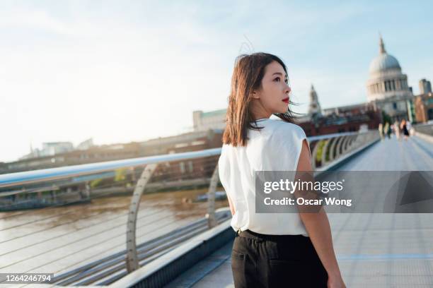 rear view of young businesswoman walking on footbridge in the city - looking behind stock pictures, royalty-free photos & images