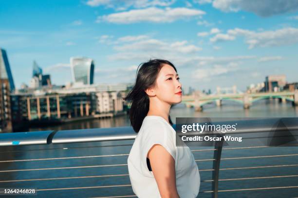 side view of young businesswoman walking on footbridge in the city - man made structure stock pictures, royalty-free photos & images