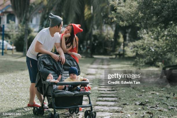 一個亞洲的中國年輕家庭在週末與雙胞胎男嬰在公共公園有結合時間。 - asian twins 個照片及圖片檔