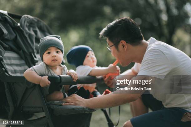 een aziatische chinese jonge familie die bondingtijd tijdens weekend bij openbaar park met hun tweelingbabyjongens heeft - asian twins stockfoto's en -beelden