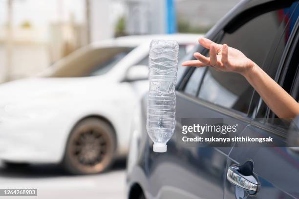 close up of hand woman throwing bottle out of car window. - throwing stock pictures, royalty-free photos & images