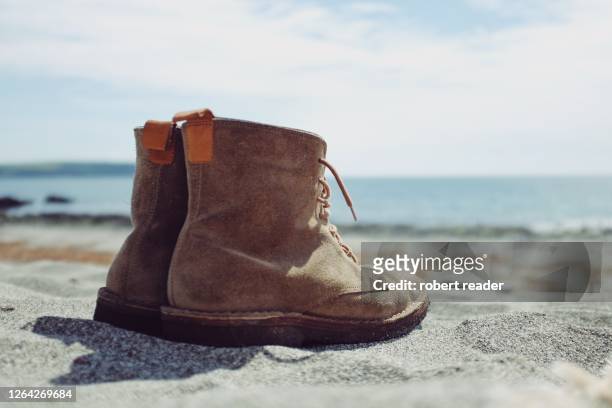 pair of boots on sandy beach - suede shoe stock pictures, royalty-free photos & images