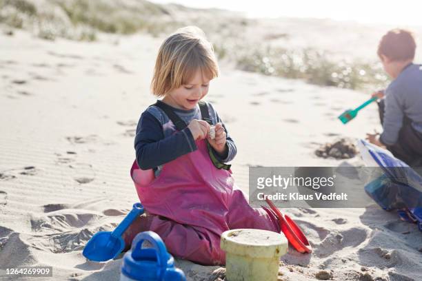 smiling girl playing with sand at beach - bornholm island stock pictures, royalty-free photos & images