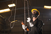 Worker operating chain hoist at factory